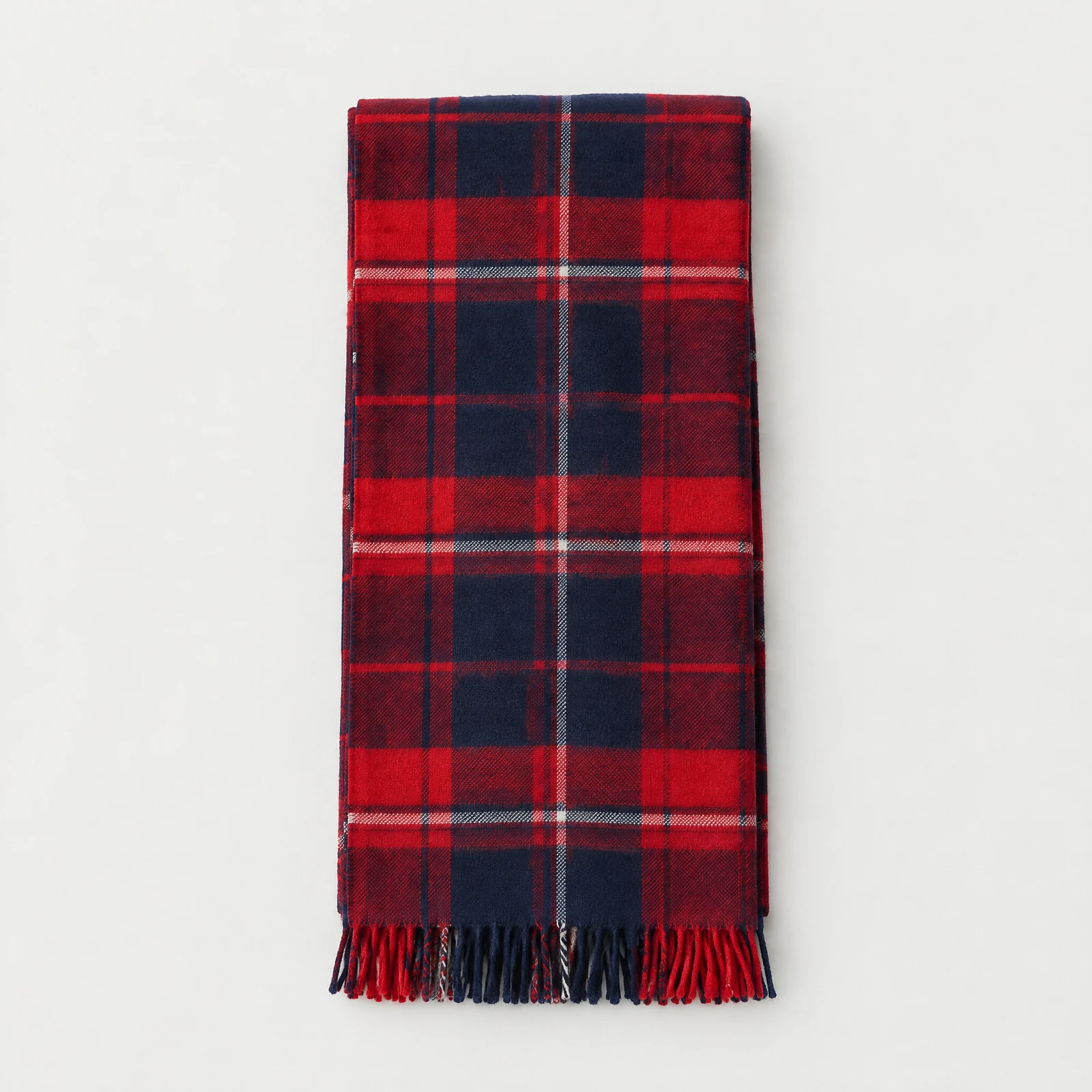 Folded red and navy plaid scarf with fringed ends on a light gray background